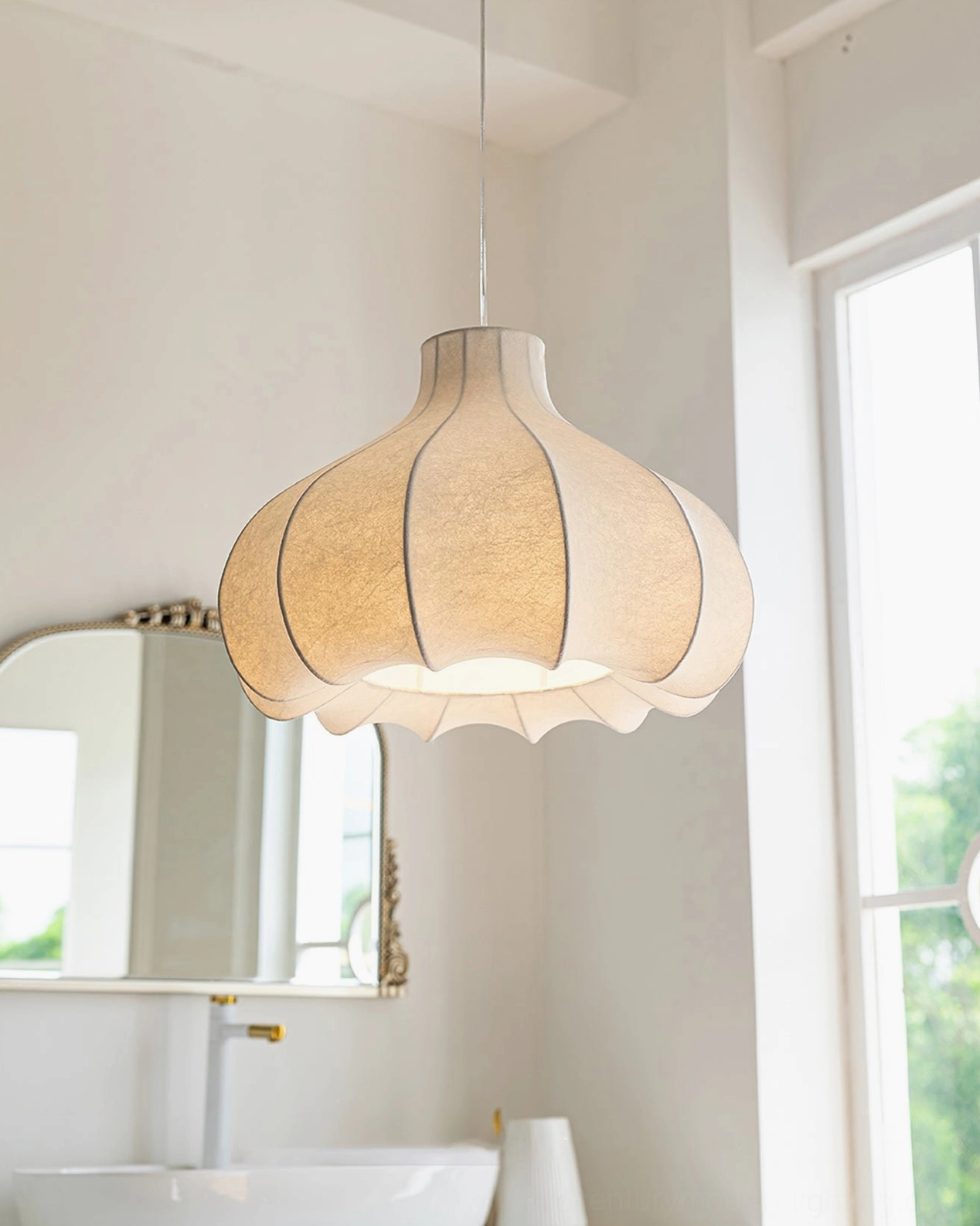 Warm beige fluted silk pendant lamp hanging above bathroom vanity with large window, soft ambient mood lighting