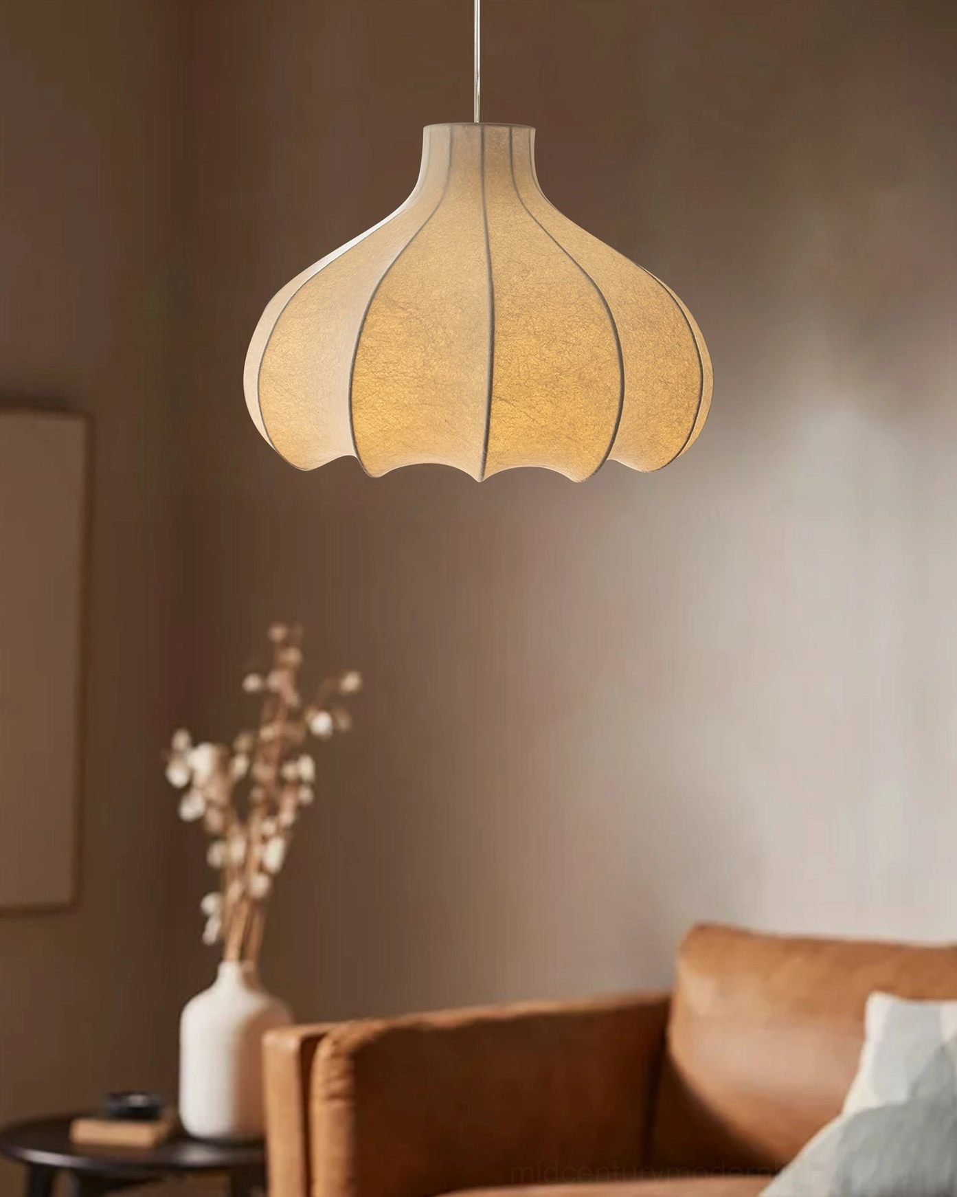 Beige fluted cocoon pendant lamp hanging in cozy living room with brown sofa, warm muted home decor ambiance
