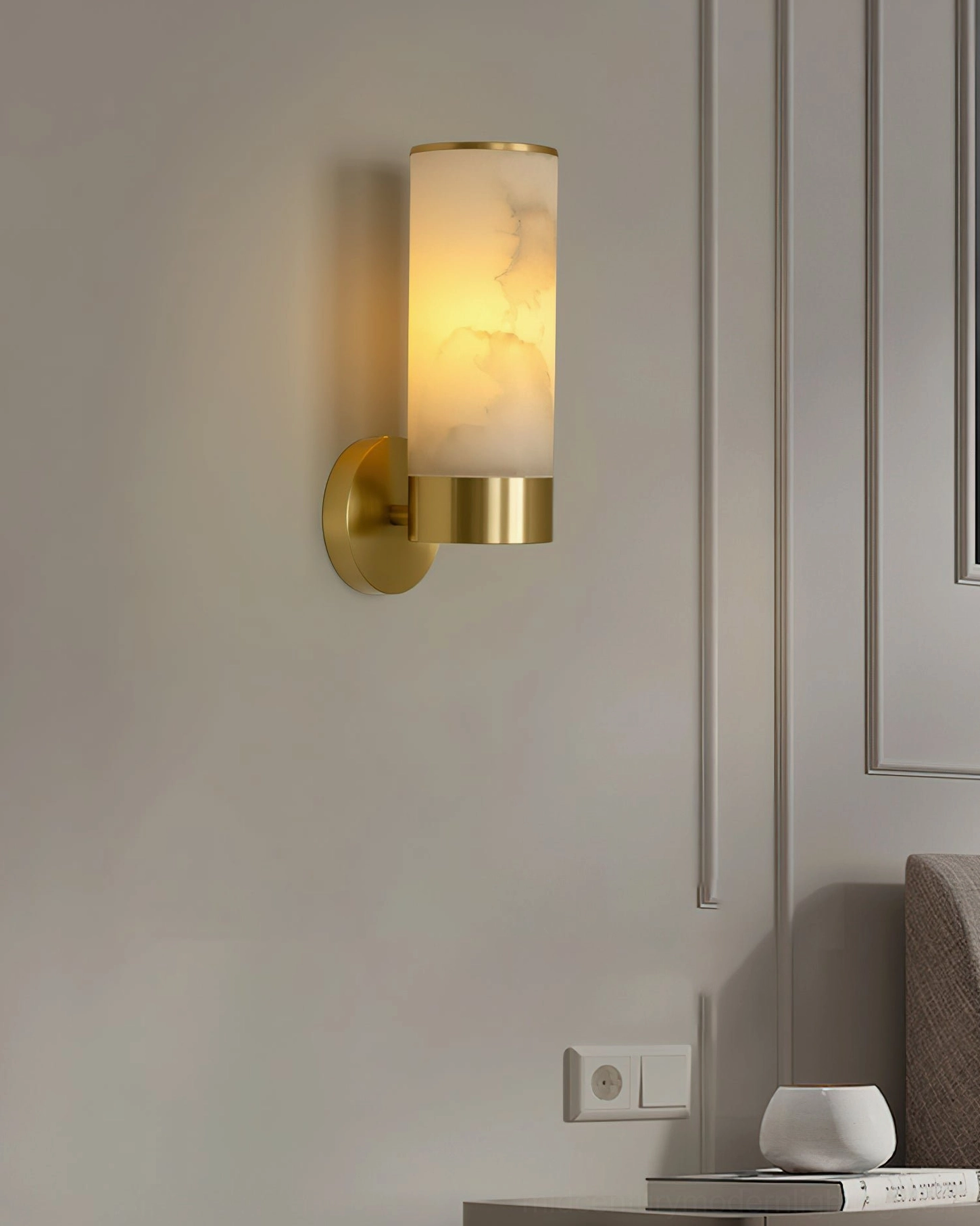 Compact brass alabaster wall sconce installed in luxury bedroom wall paneling, minimalist design with soft ambient lighting