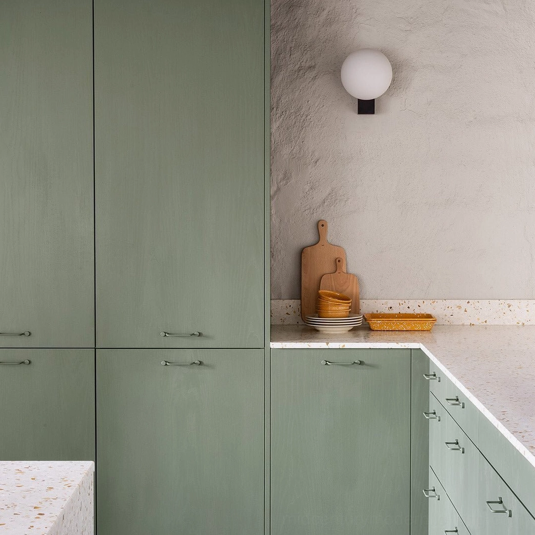 Compact geometric globe wall light in modern green kitchen with matte black base and small frosted glass diffuser