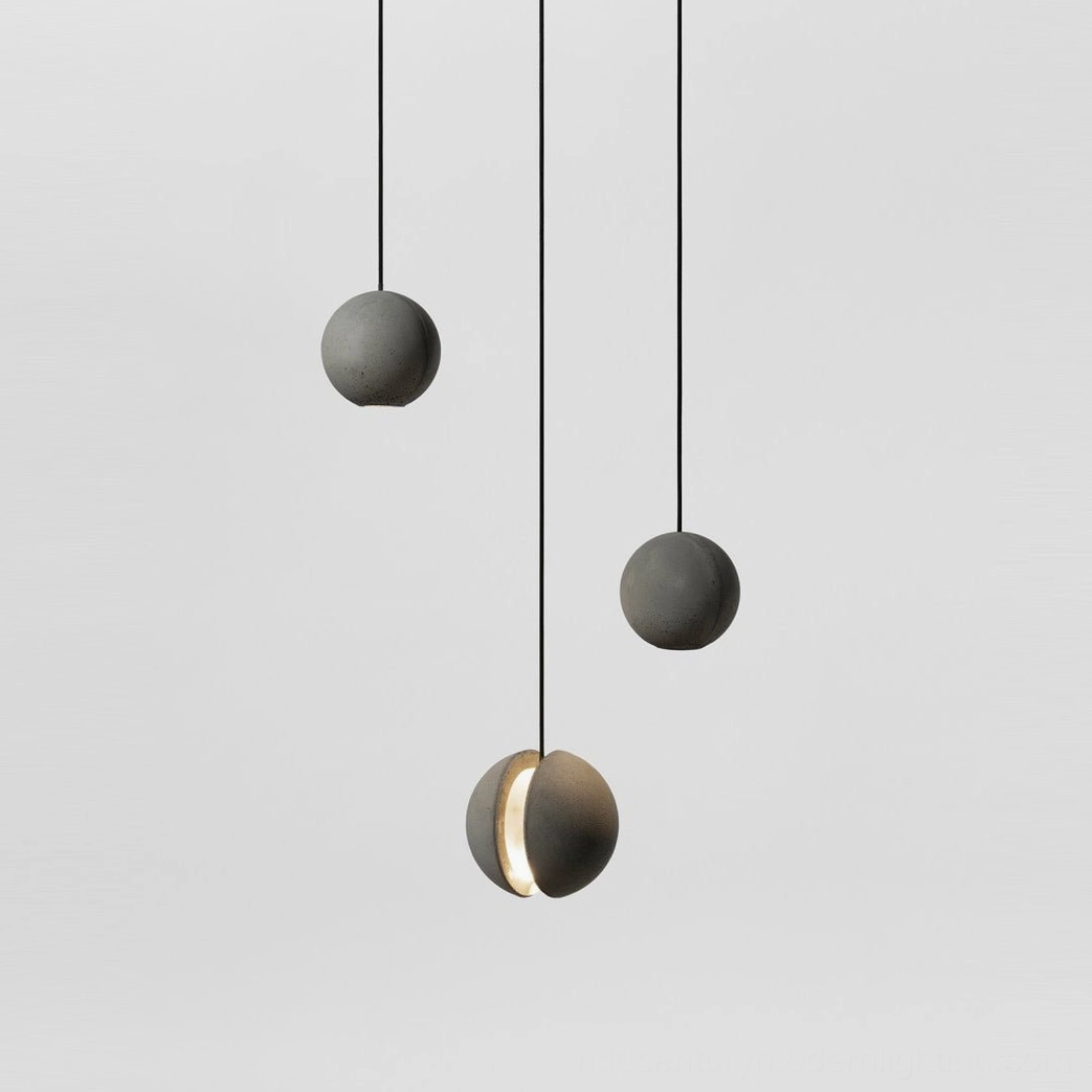 Set of concrete pendant lights hanging from above, mixed solid and split spherical designs with black suspension cords