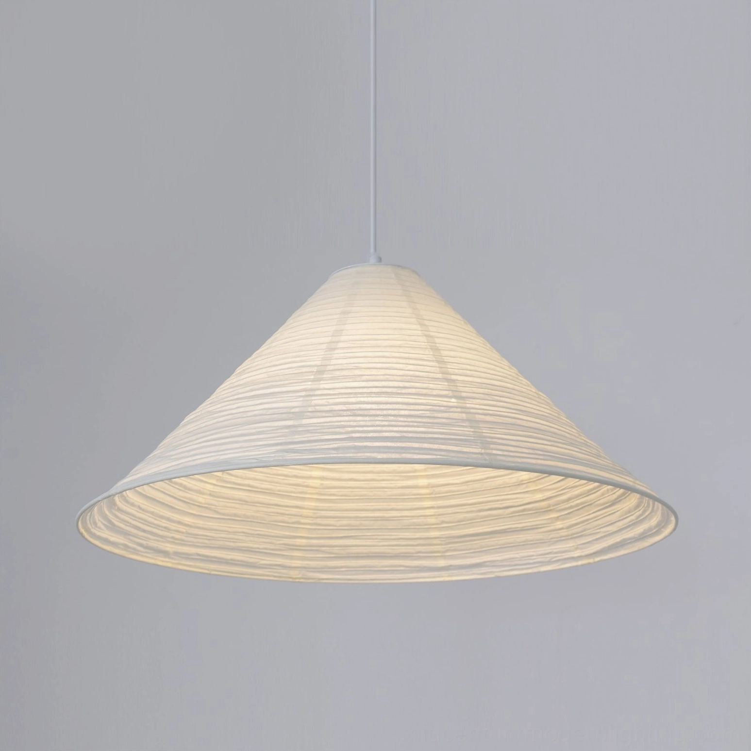 Cone Washi Pendant Lamp three-quarter front view against neutral grey wall with warm inner glow