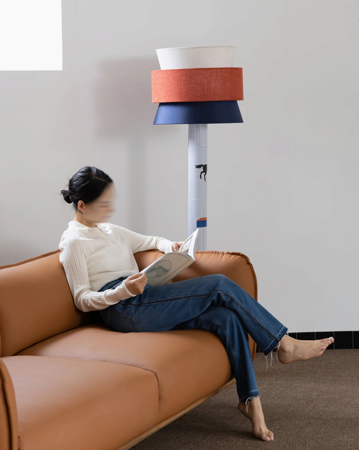 Modern playful standing lamp providing warm lighting beside brown leather sofa, contemporary reading nook setup