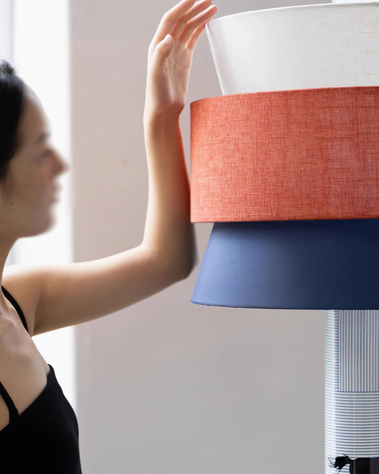 Striped Pony Floor Lamp side profile near window with woman reaching toward shade, matching blue and orange tones