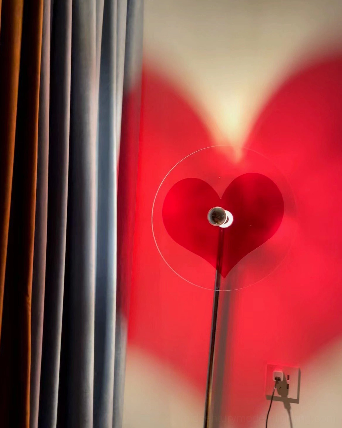 Red heart shadow floor lamp illuminating contemporary styled room with warm light projection