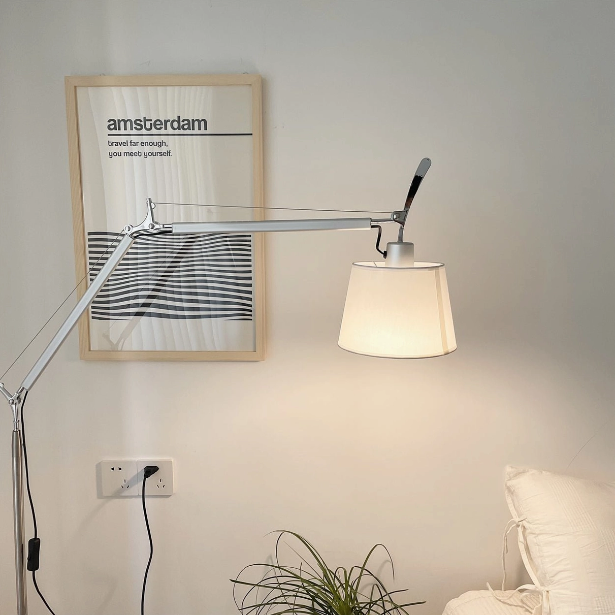 Contemporary swing arm floor lamp with sleek silver metal design near minimalist wall art, side perspective view