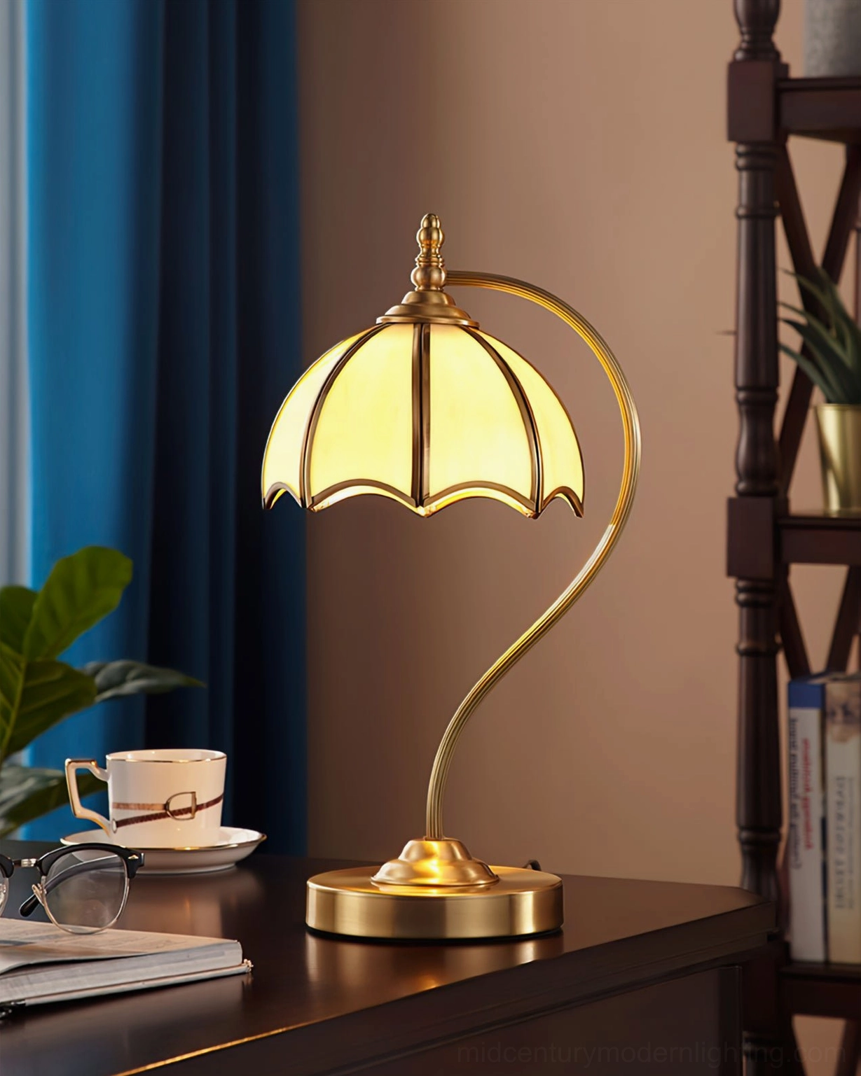 Contemporary umbrella table lamp with brass frame beside desk accessories and bookshelf