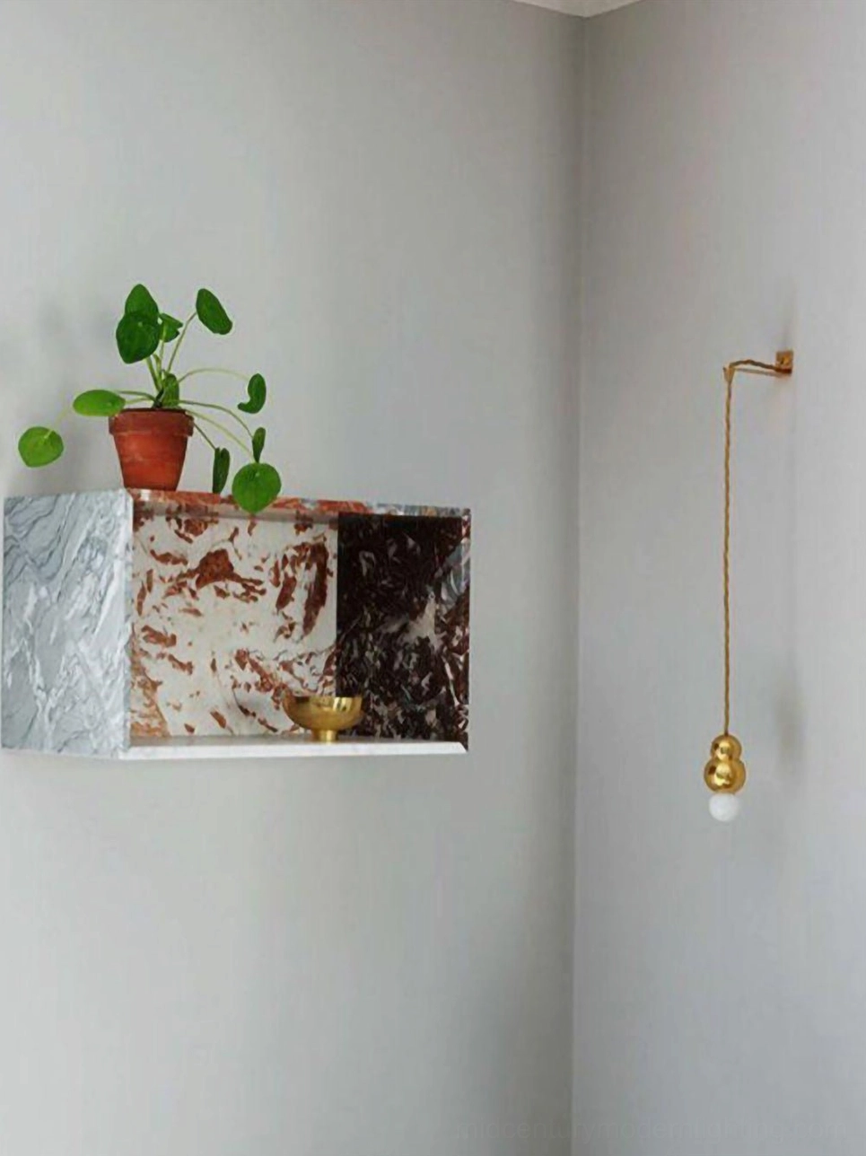 Corner wall-mounted brass ball sconce, minimalist apartment, frosted glass with marble shelf, green plant