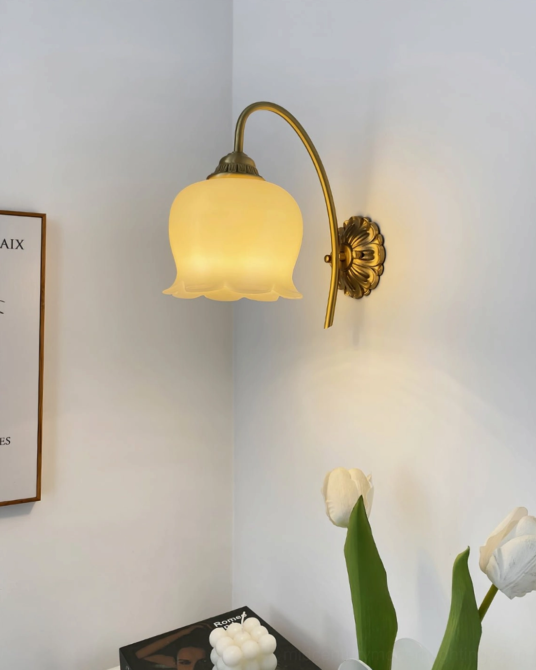 Warm-toned frosted glass lily of the valley wall lamp in corner wall setting with tulip flowers