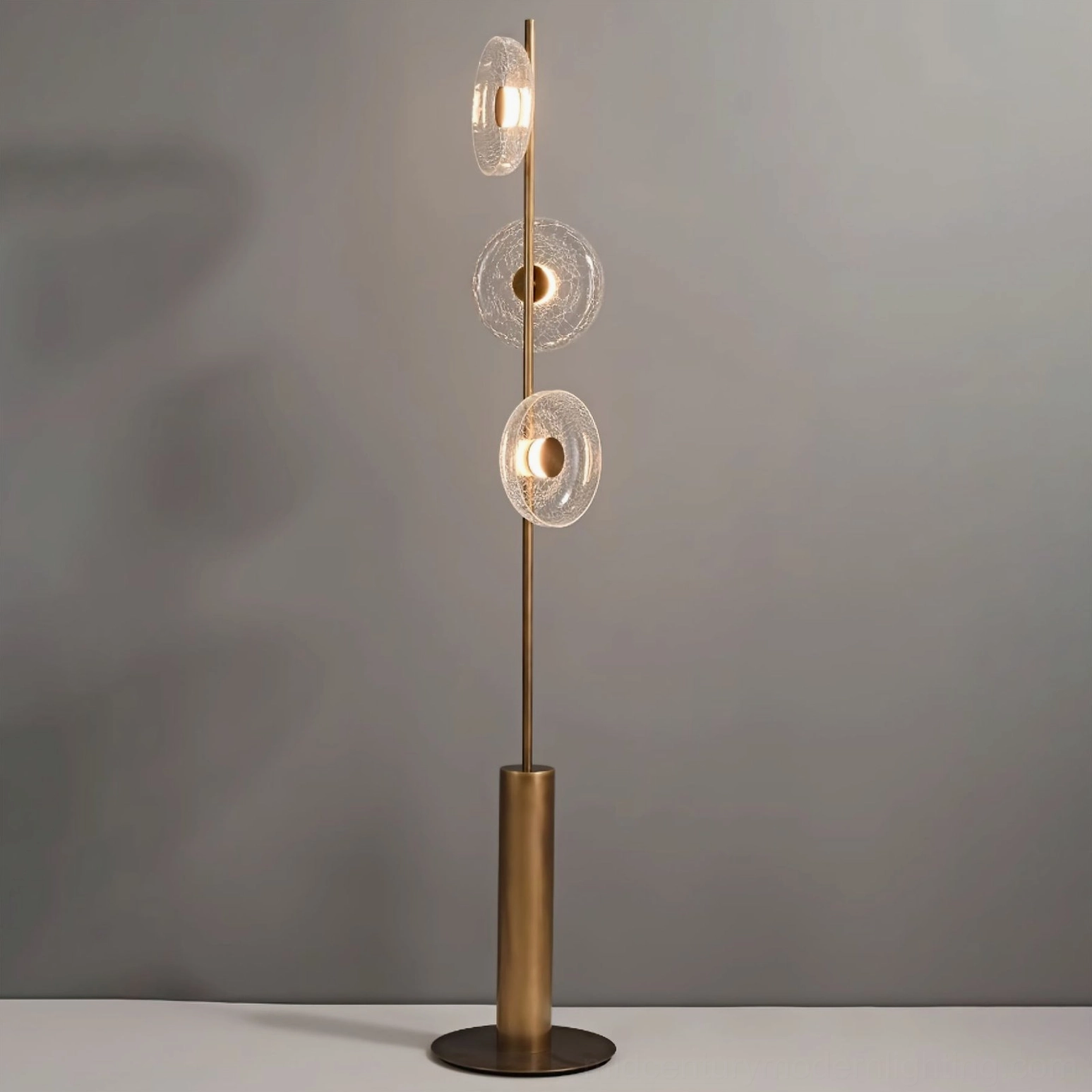 Modern floor lamp with tiered crackle glass shades emitting warm glowing LED light against gray backdrop