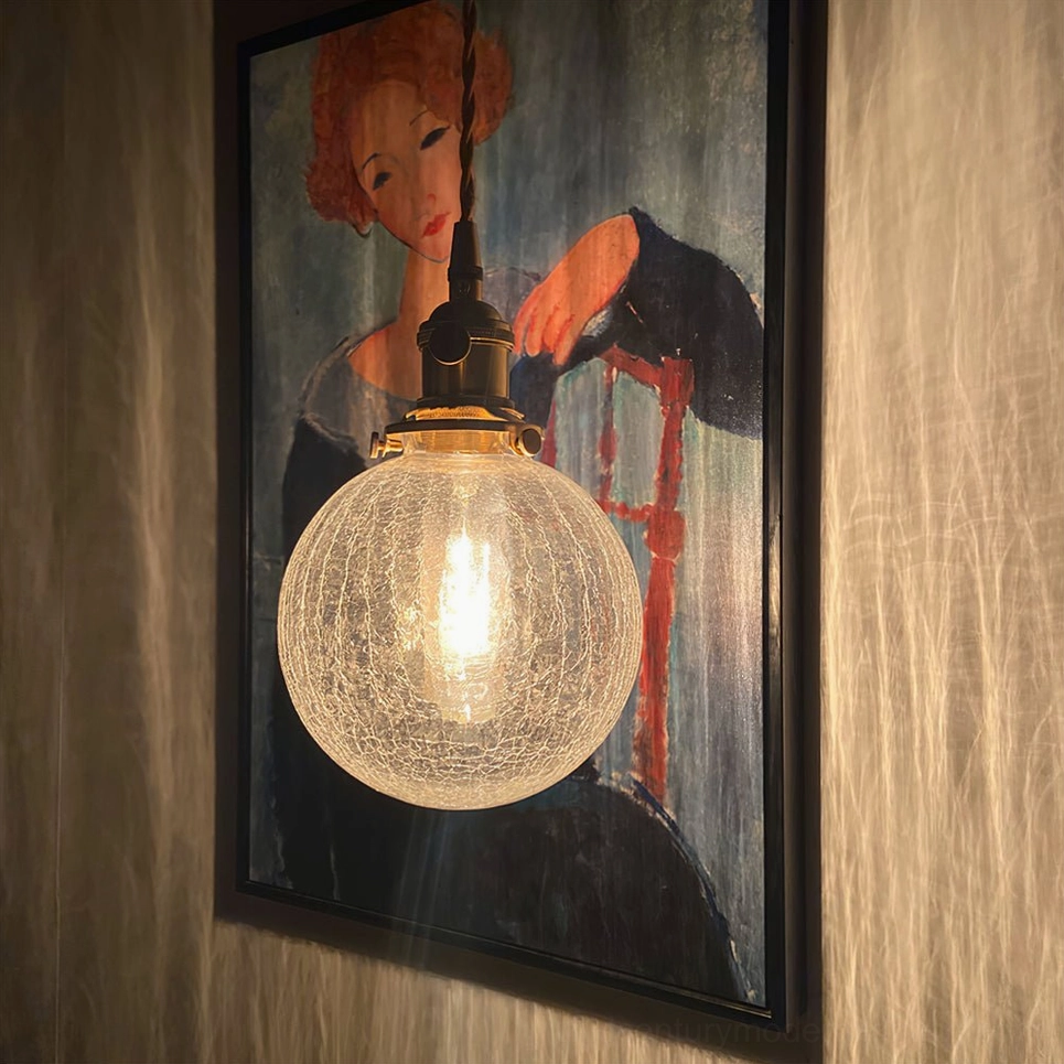 Crackle glass pendant light fixture showcase with warm illumination highlighting textured glass and brass construction details