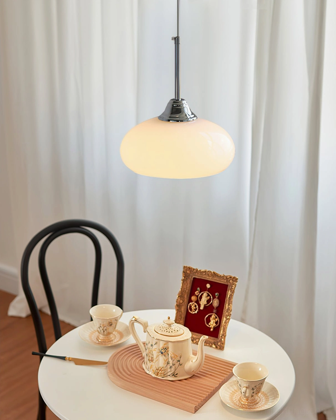 Lit Cream Bell Pendant Light above vintage dining table with tableware and retro decor