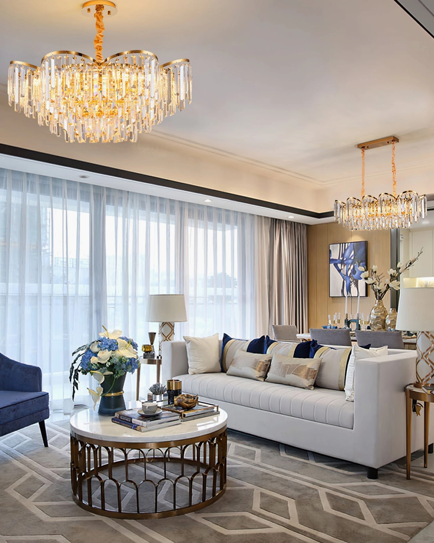 Matching pair of gold crystal chandeliers in open-plan modern living room with neutral luxury decor