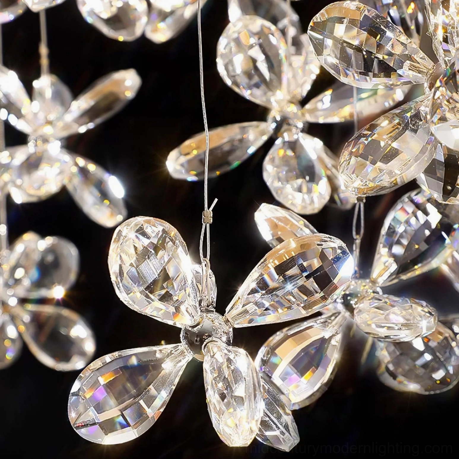 Macro close-up of crystal butterfly pendant flowers, faceted clear crystal petals with metal flower centers, diamond-cut light refracting through glass