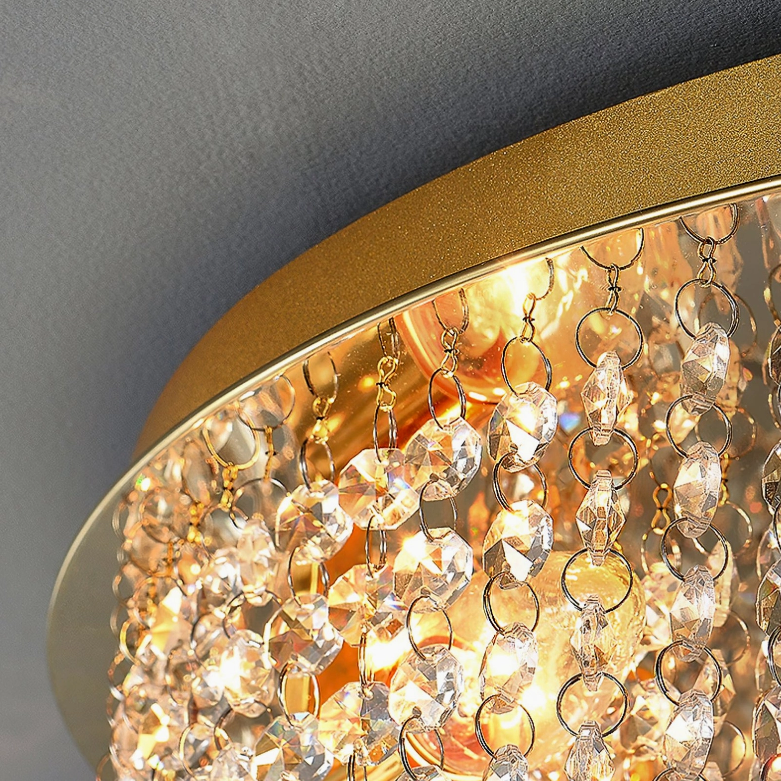 Side perspective of matte gold ceiling lamp with dense hanging clear crystals illuminated in warm light