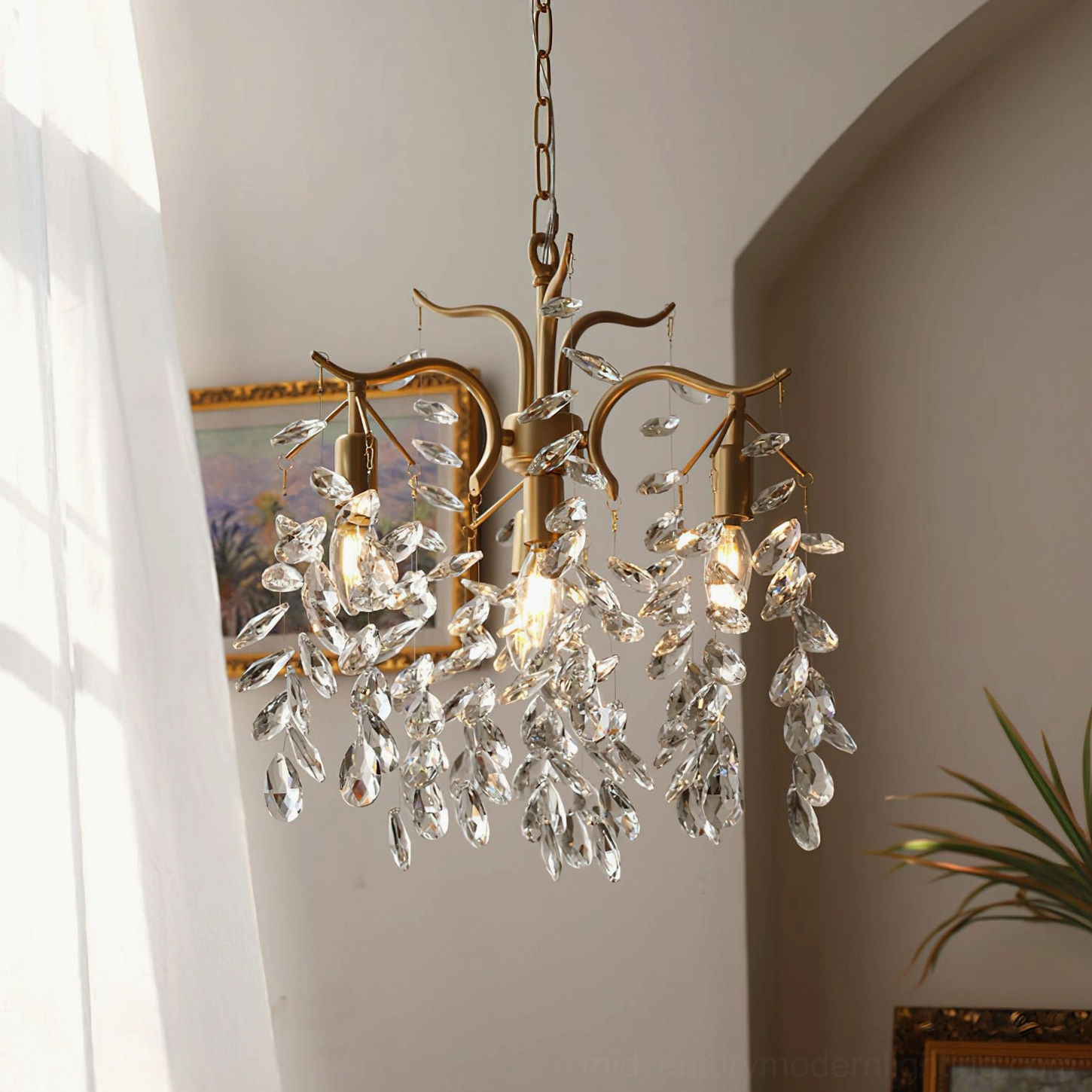 Gold crystal leaf pendant light suspended in sunlit arched doorway with delicate hanging chain and faceted crystal decorative elements