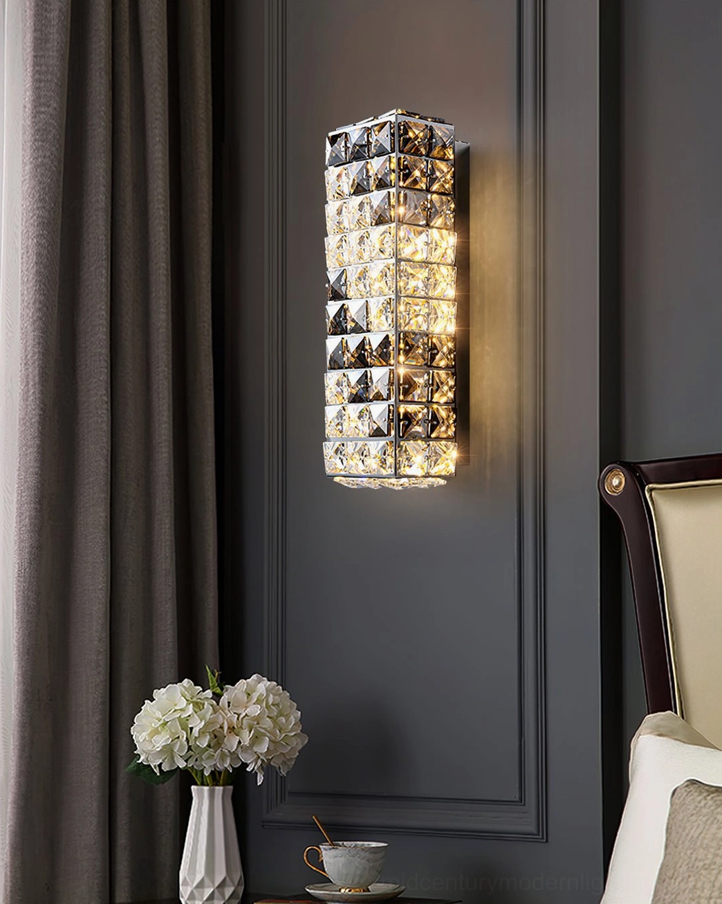 Contemporary crystal wall sconce installed in luxury bedroom with dark accent wall and modern decor