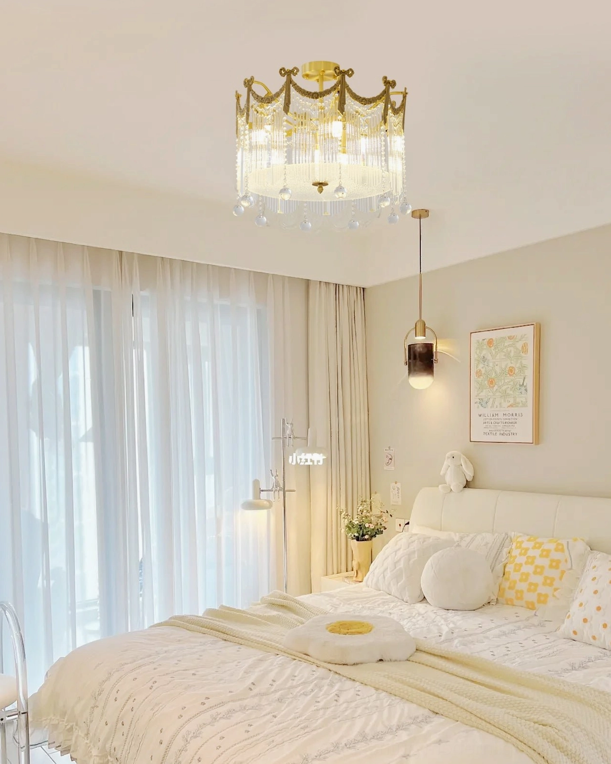 Crystal chandelier ceiling lamp in minimalist bright bedroom with white linens and simple decor