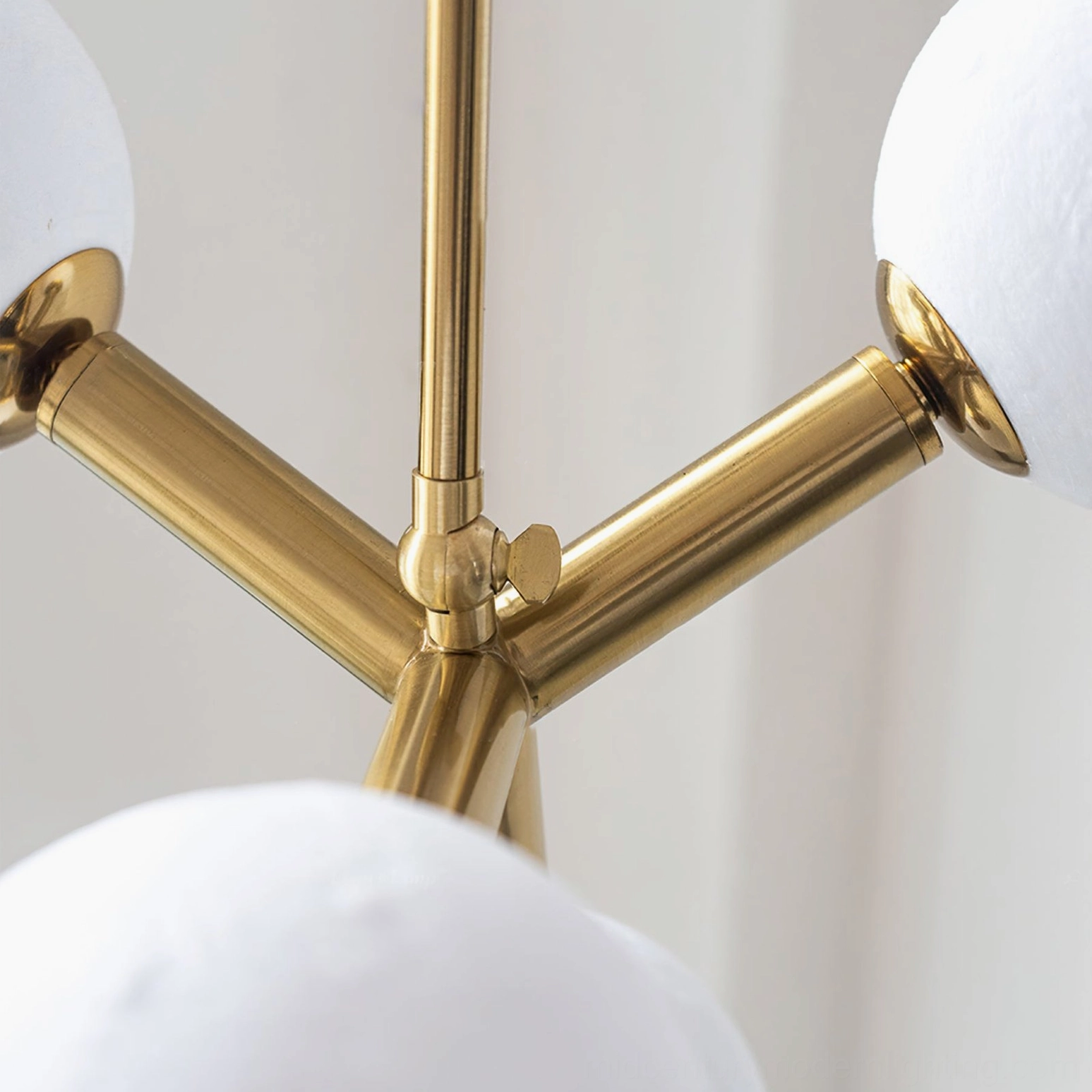 Close-up detail of brass metal joint connecting moon glass shade on Dallas Planet chandelier