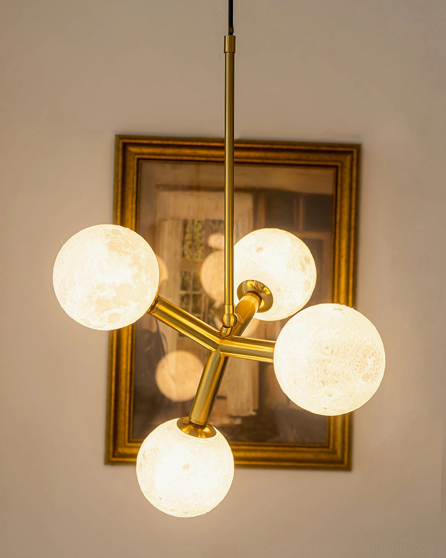 Dallas Planet pendant chandelier unlit with frosted moon shades and polished brass metalwork in home setting