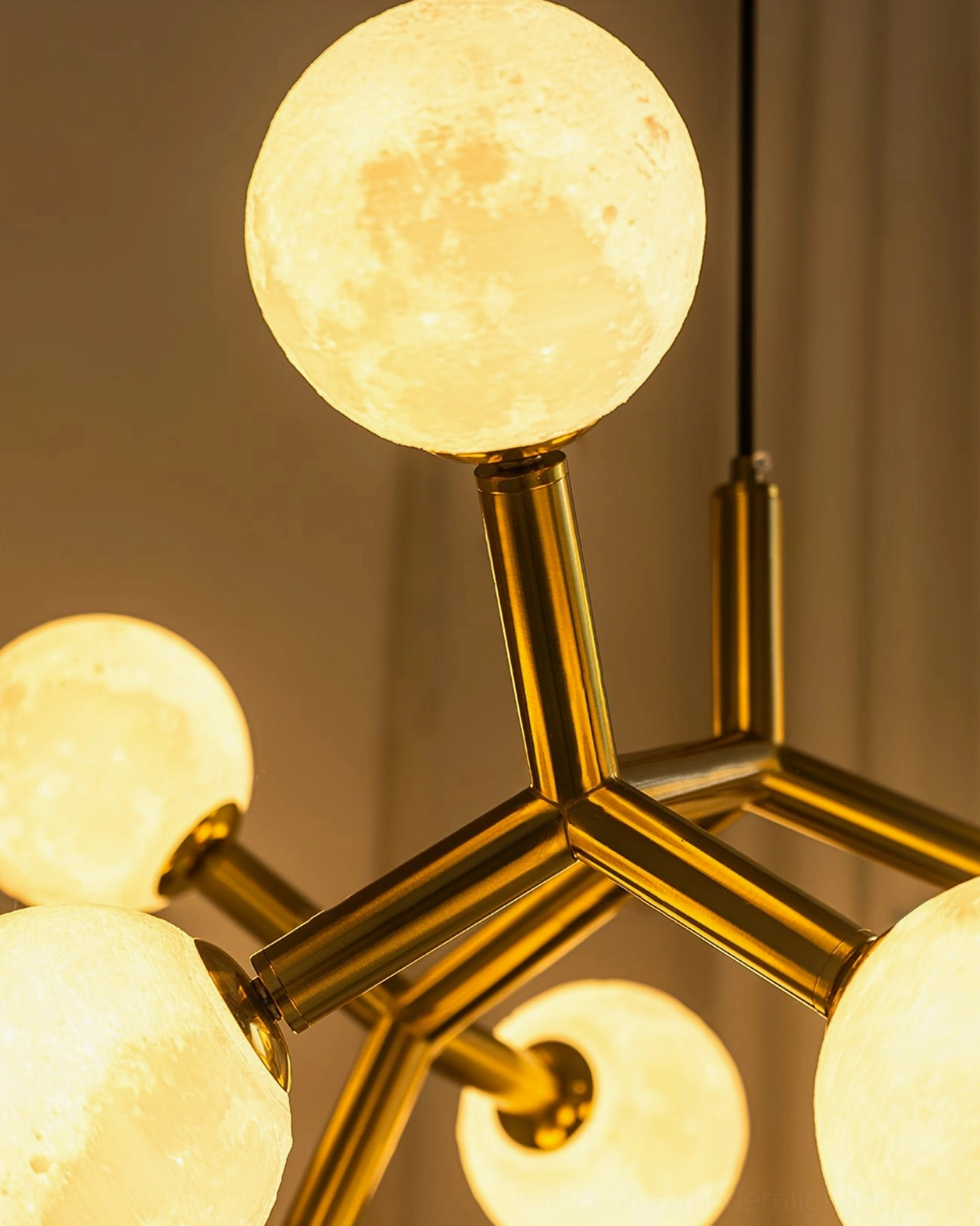 Low-angle macro view of glowing moon glass spheres on Dallas Planet Sputnik chandelier with brass structure