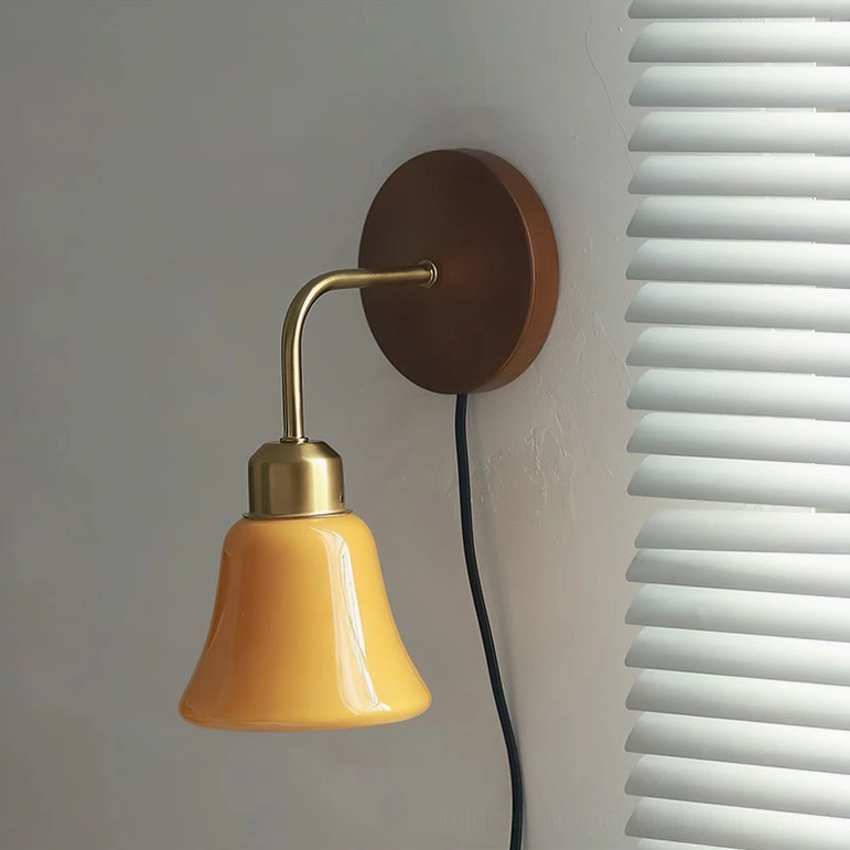 Daphne Pastel Wall Sconce three-quarter side view unlit on white louver blinds, showcasing smooth ceramic shade and curved brass arm design details
