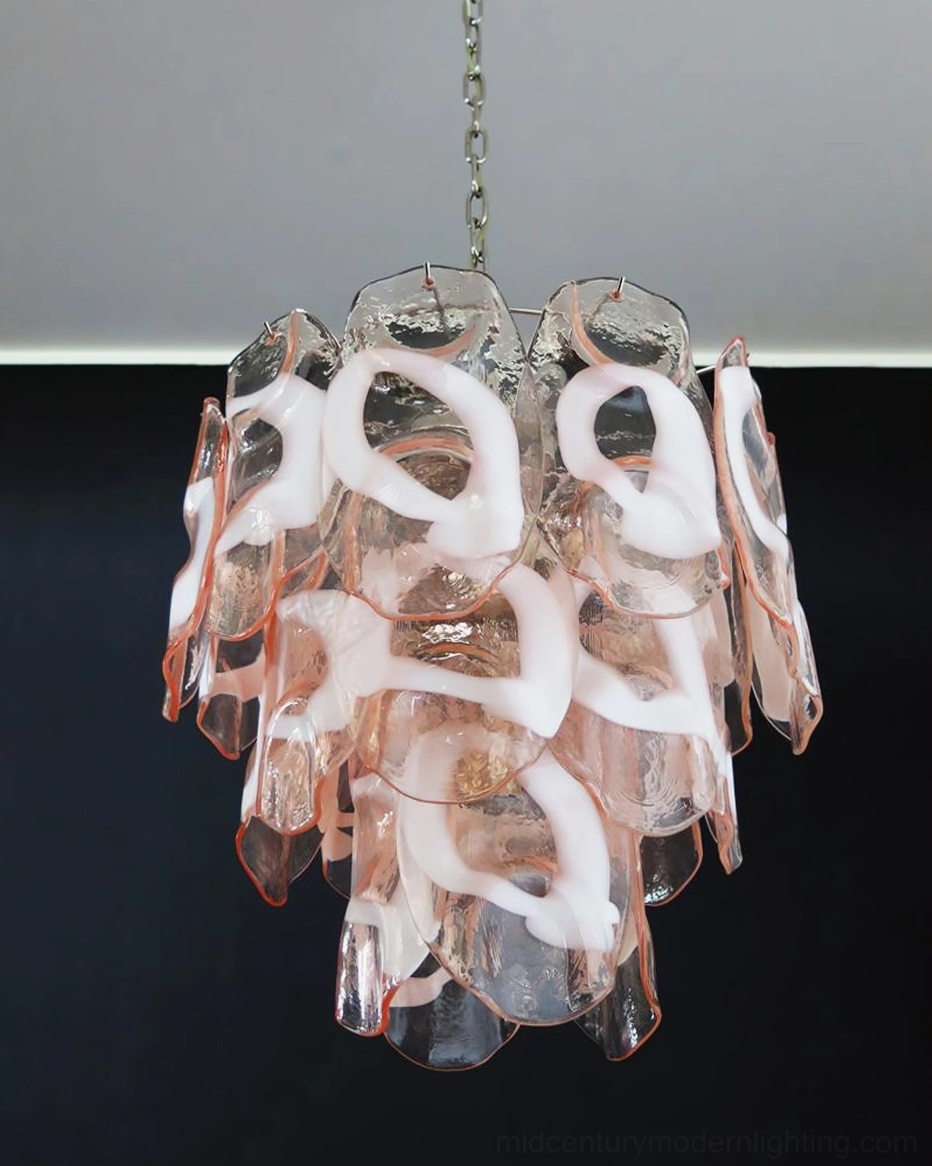 Multi-tiered Delara pink and white glass chandelier with prominent white glass accents, front hanging view against dark background