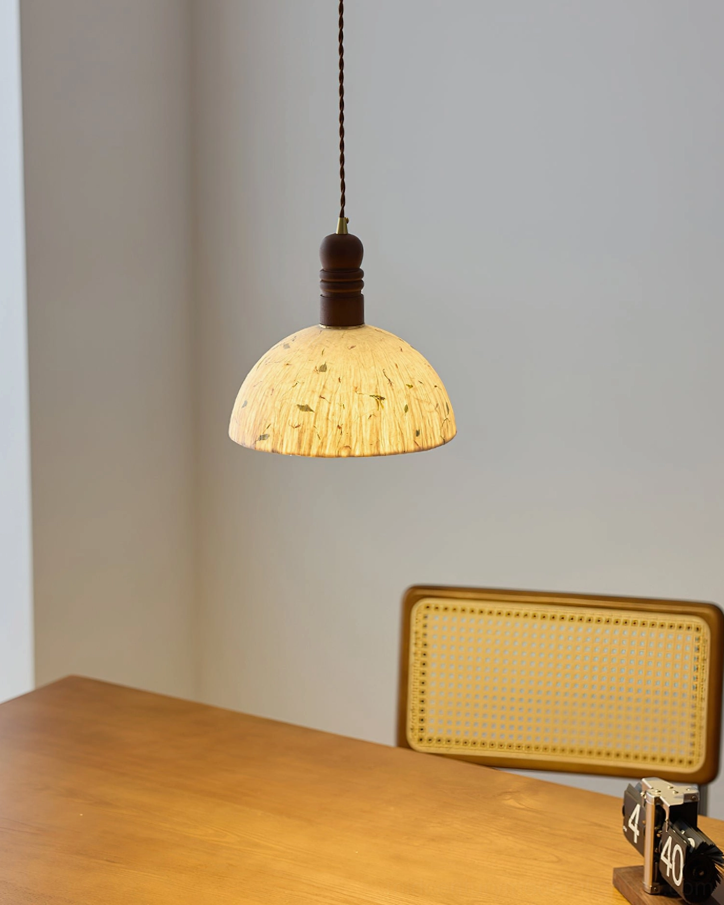 Small Diana pendant light hanging in dining nook with warm beige shade and rattan chair styling