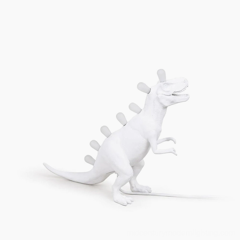 Dinosaur table lamp with glowing LED spine, rear three-quarter view showcasing matte white resin construction
