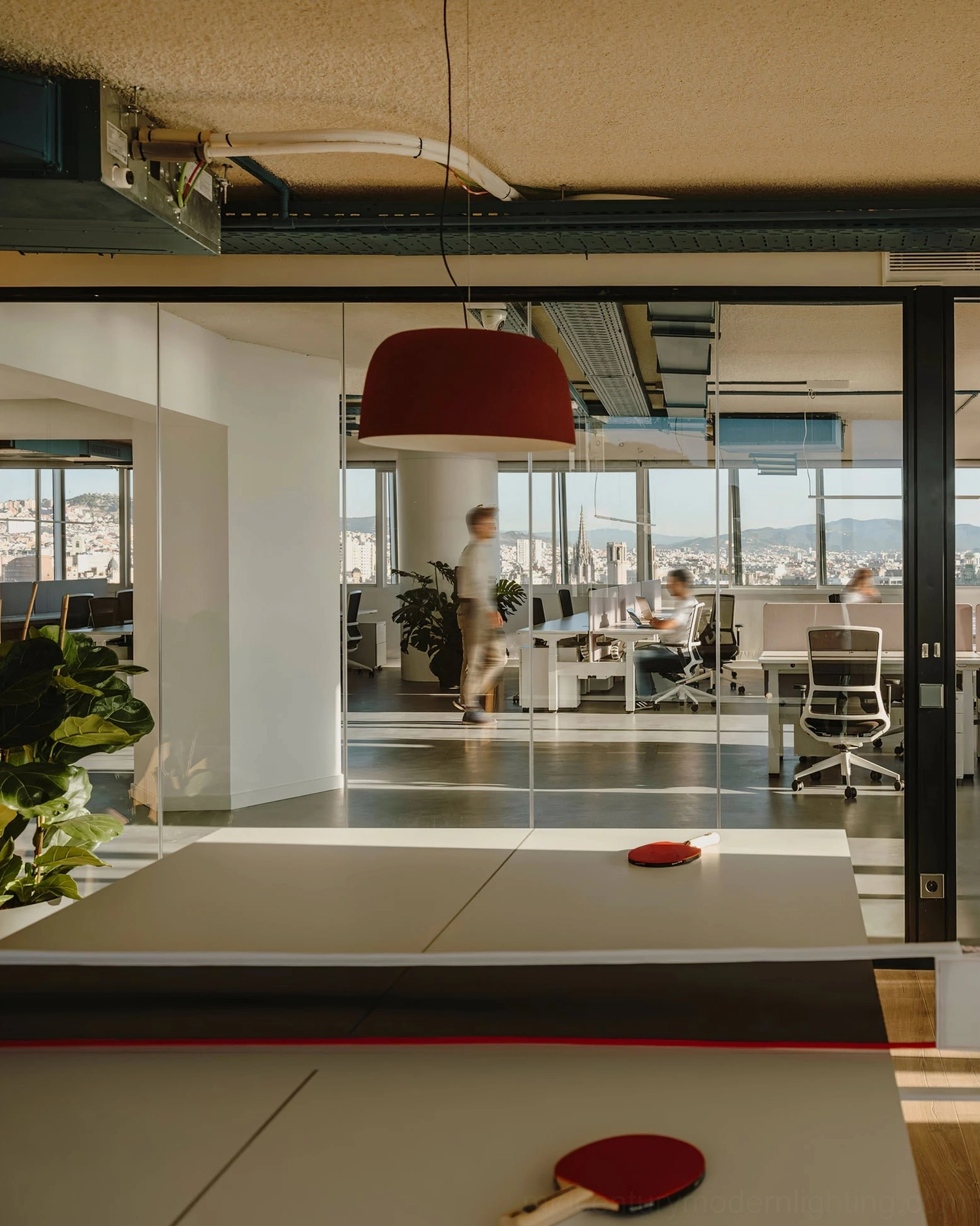 Burgundy Djembe pendant lamp in open-plan office with ping pong table and city view windows
