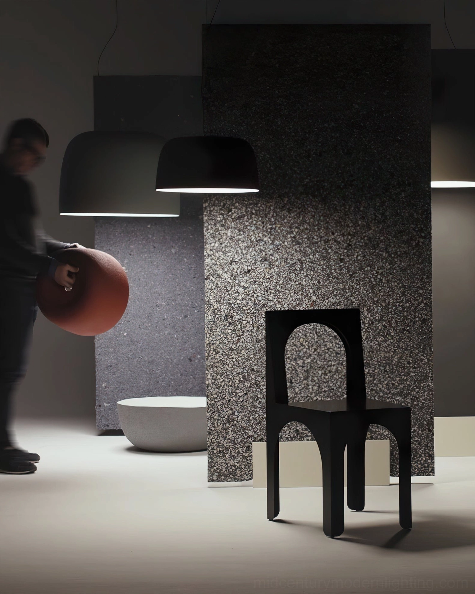 Dark-toned Djembe pendant lamps in minimalist showroom with textured accent wall and modern chair