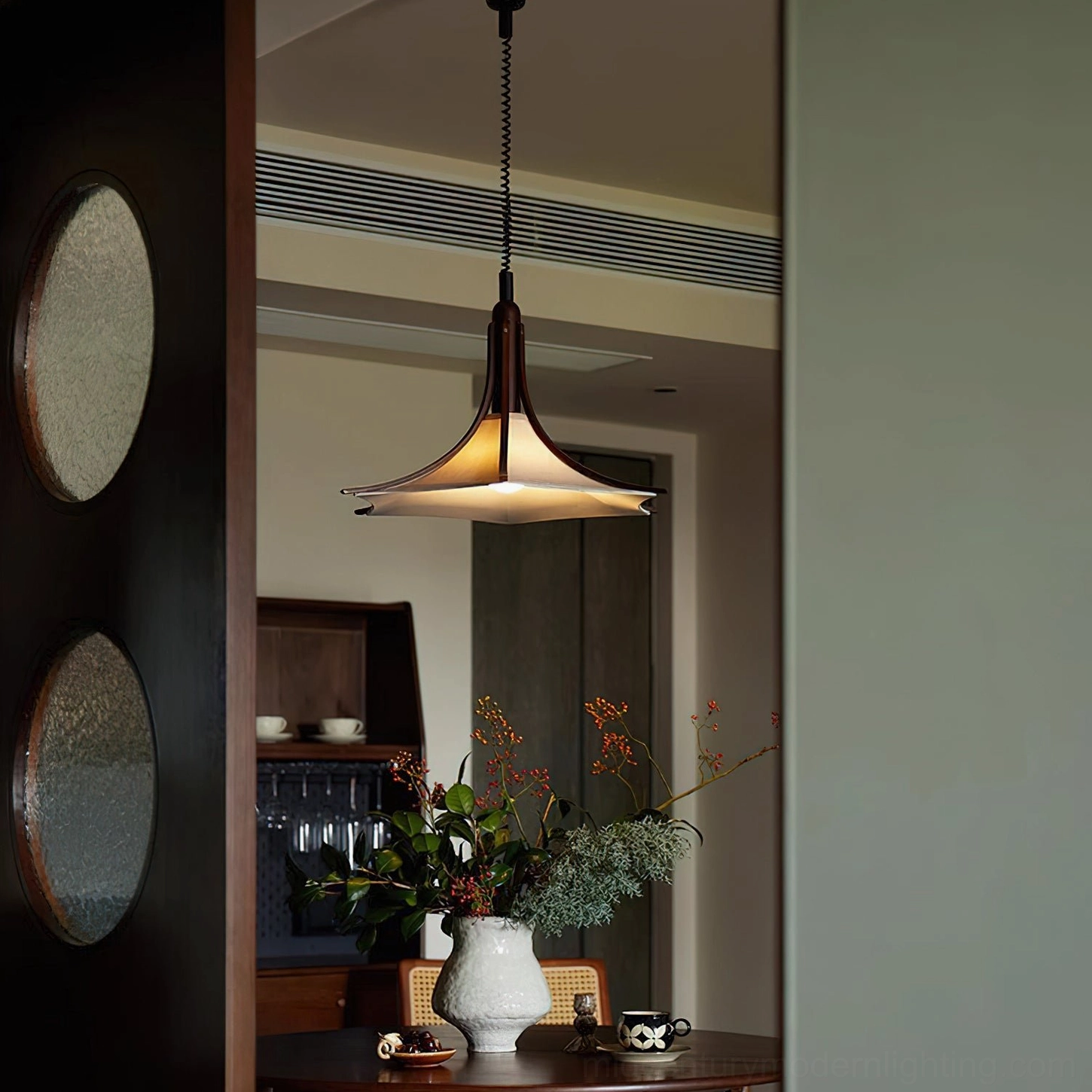 Modern pendant light above dining area with warm ambient lighting and floral table decor