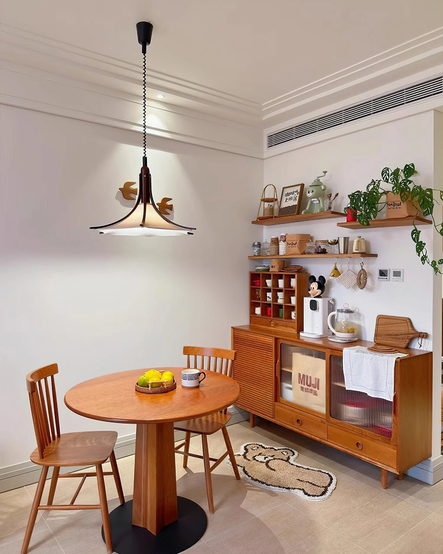 Mid-century warm pendant lamp in kitchen breakfast nook with wooden cabinet and green plants