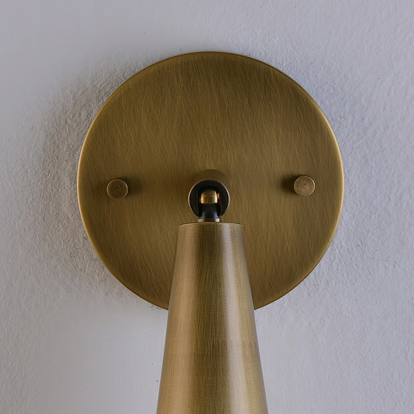 Donna wall sconce overhead macro view of round brass backplate and central pivot joint