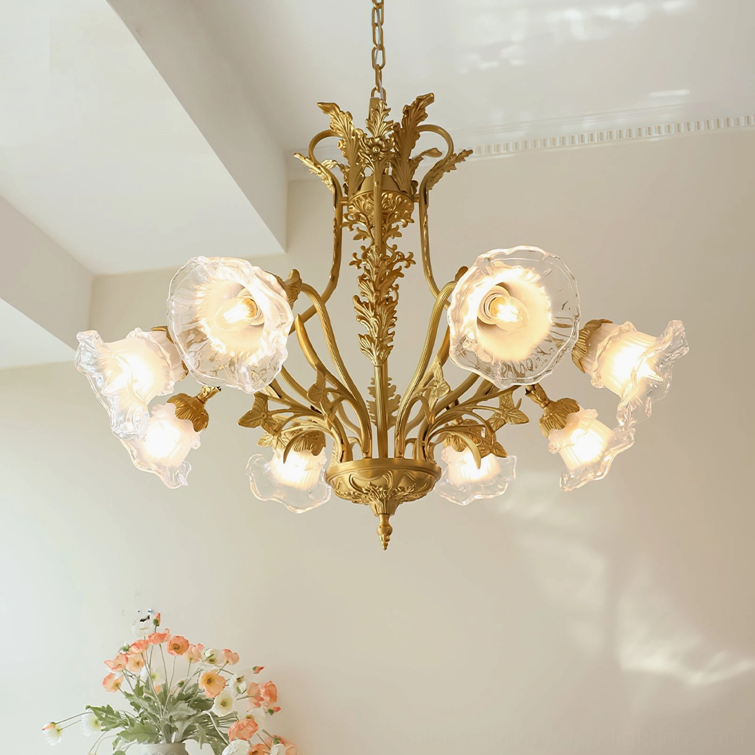 Lit Dore flower chandelier casting warm romantic light in cozy dining room with floral table arrangement