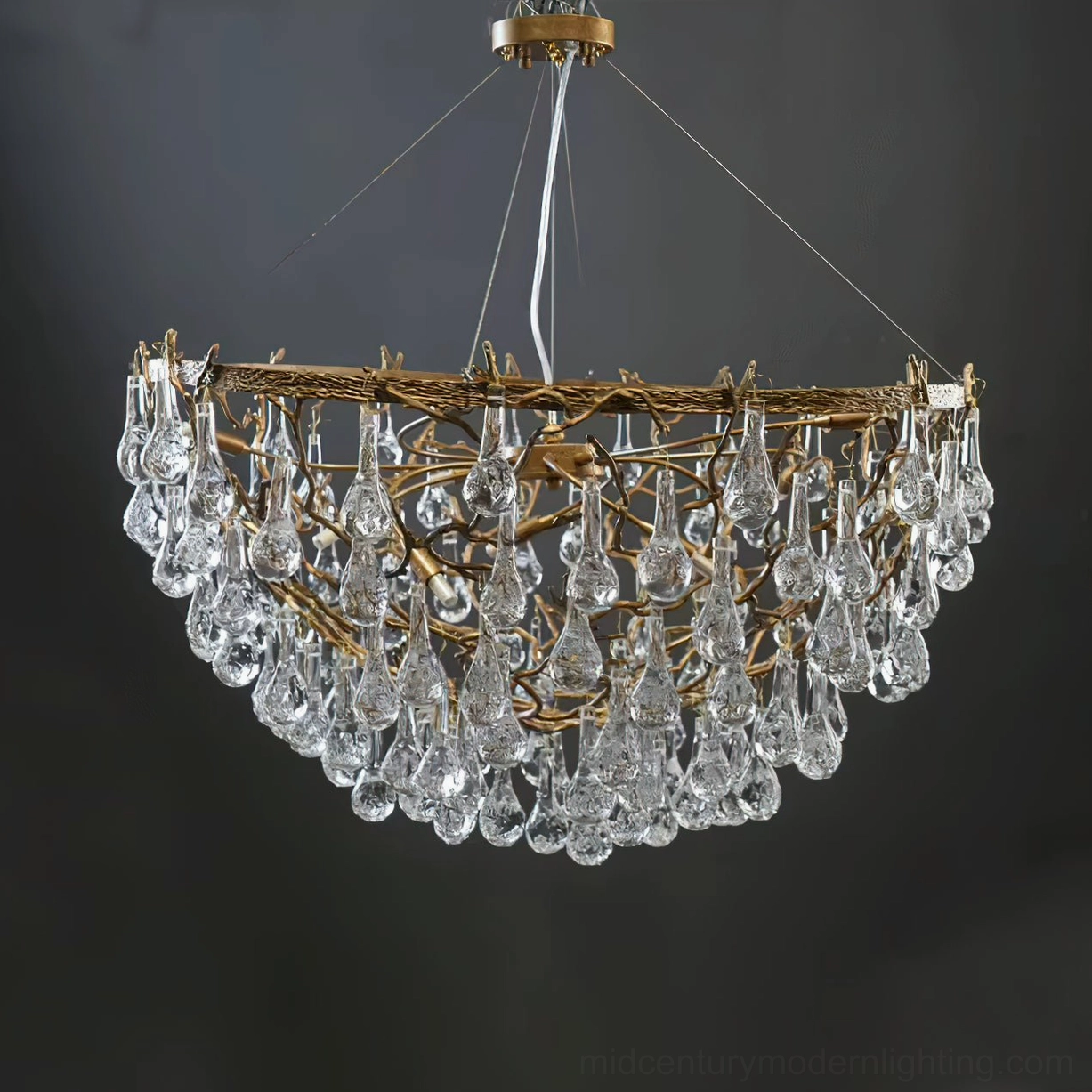 Doris antique brass chandelier close-up showing layered teardrop crystal drops with cascading refraction pattern against dark studio backdrop
