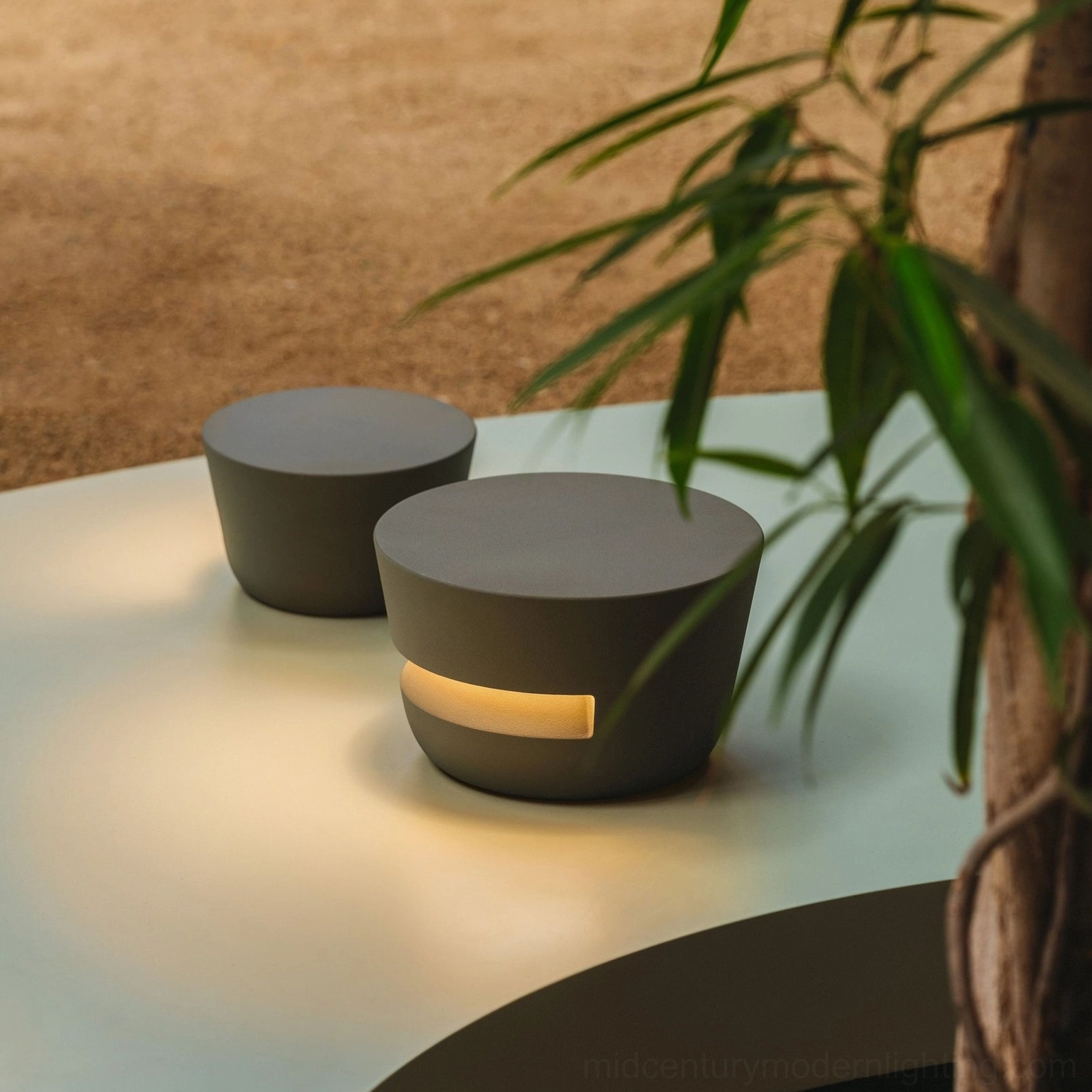Two Dots outdoor table lamps on patio table - close-up top view showing matte finish and side light band detail