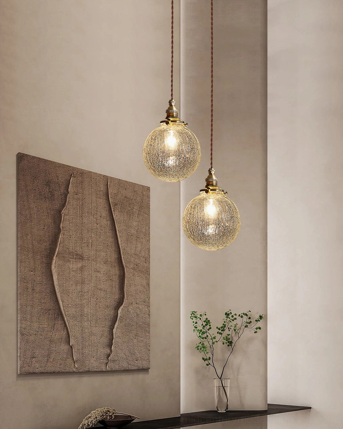 Dual crackle glass pendant lights mounted on minimalist wall with textured wall art and warm ambient interior lighting