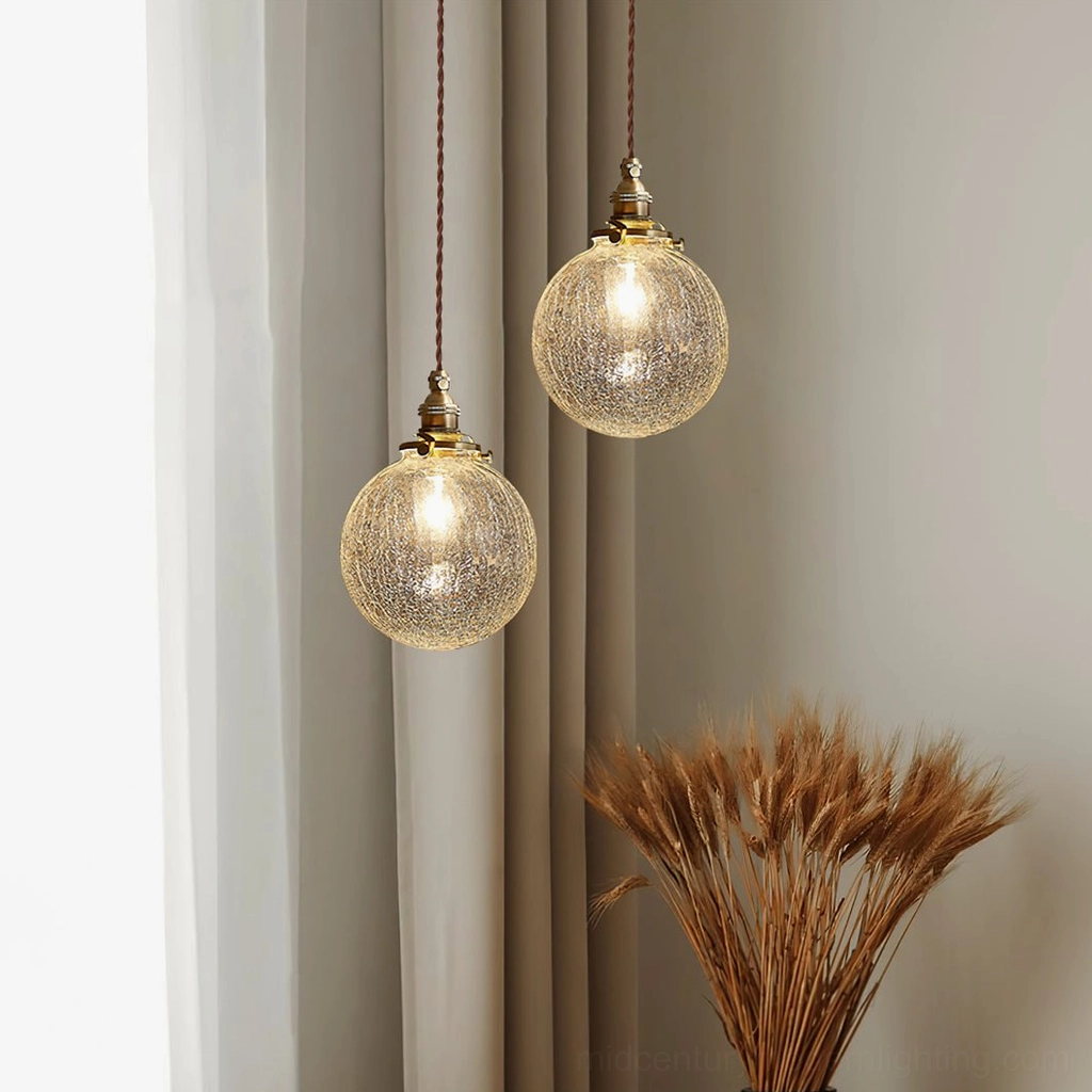 Pair of crackle glass pendant lights by curtained window with dried wheat decoration and soft natural daylight