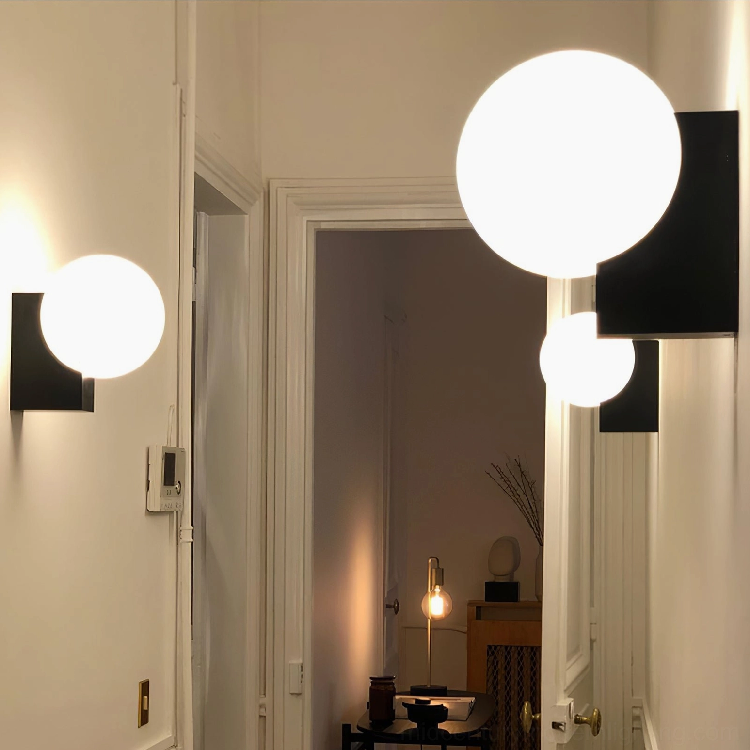 Pair of minimalist geometric wall sconces in hallway corridor with multiple frosted glass globes and matte black brackets