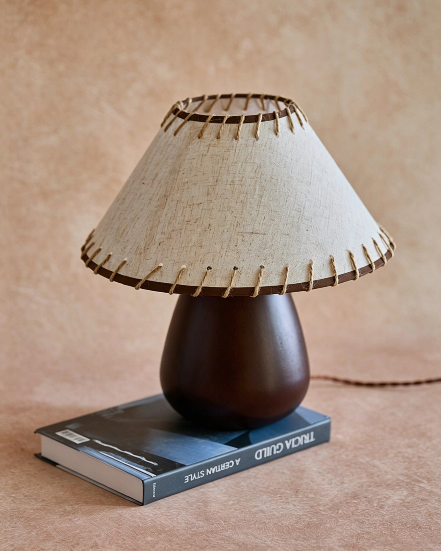 Douglas walnut table lamp base resting on decorative hardcover book showing scale and proportion