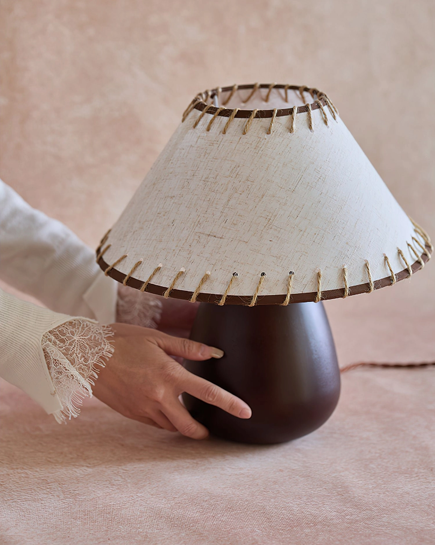 Hands holding Douglas walnut lamp showing craftsmanship, twisted power cord detail, lace sleeve accent