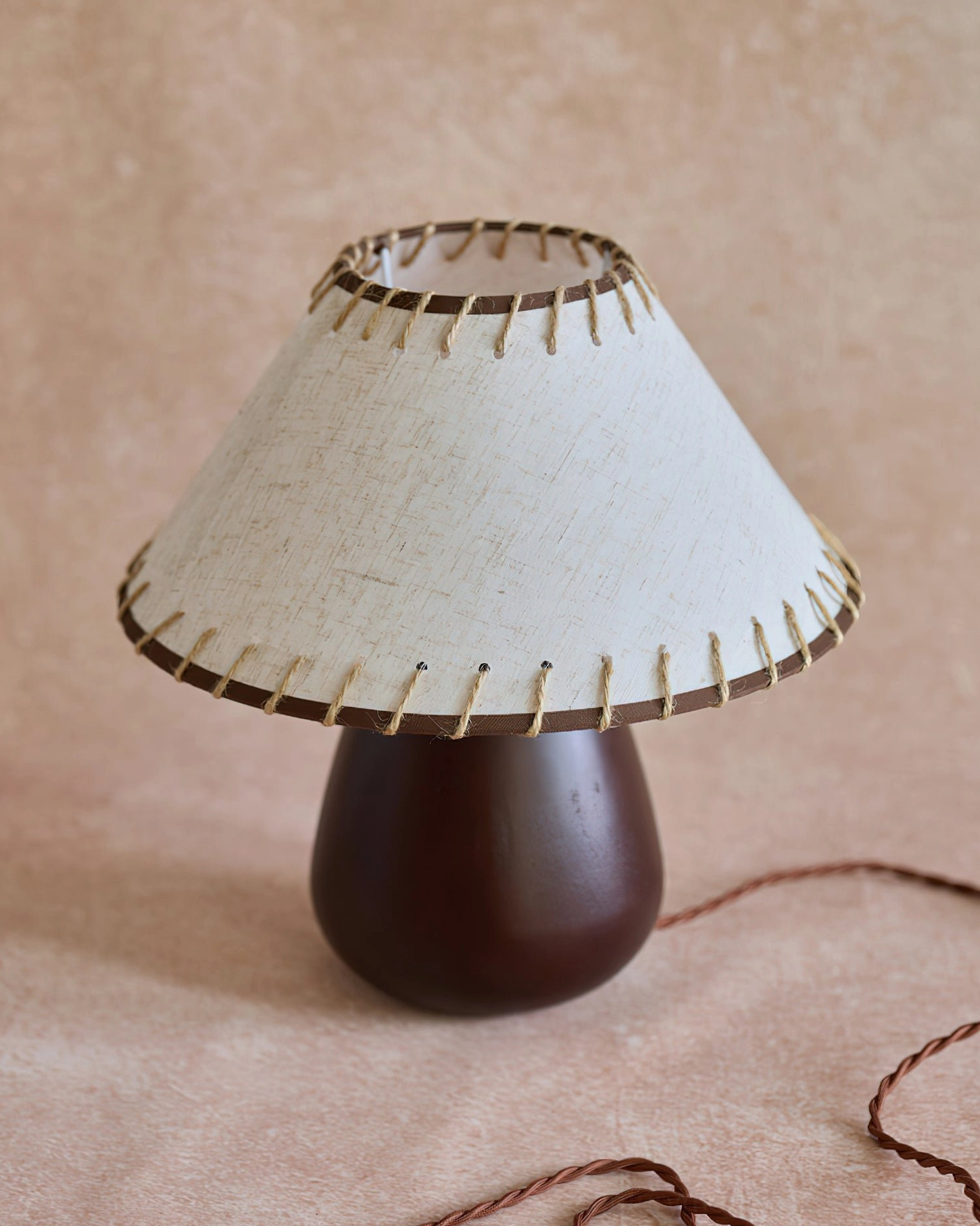 Unlit Douglas walnut table lamp showing beige linen shade and twisted brown power cord on matte table