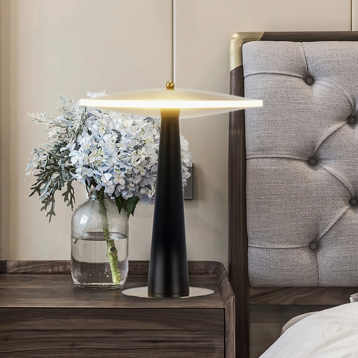 Gold and black architectural lamp paired with white hydrangea flowers on table