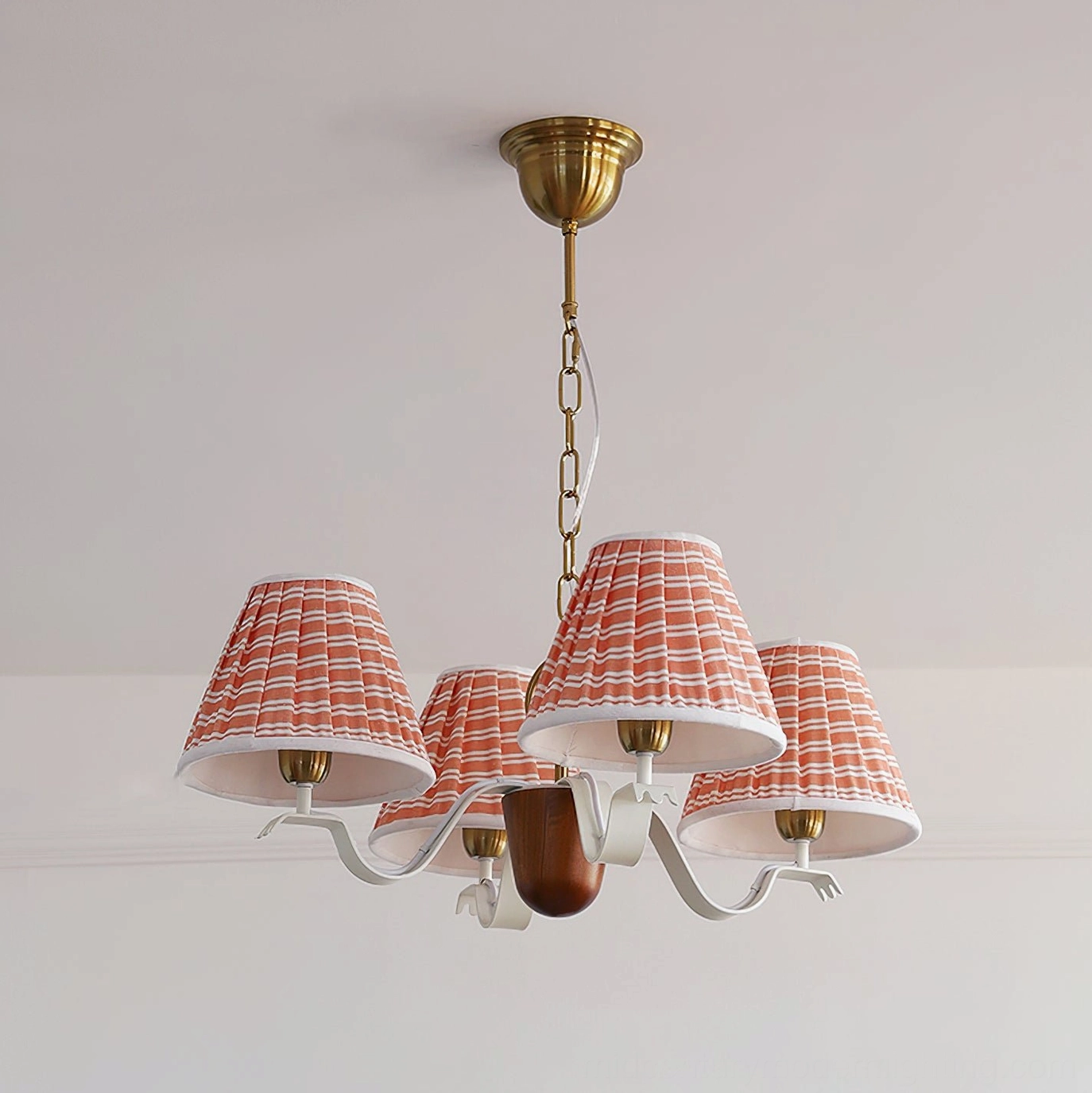 Fabric pendant light fixture with beige pleated shades and brass elements in corner wall interior styling