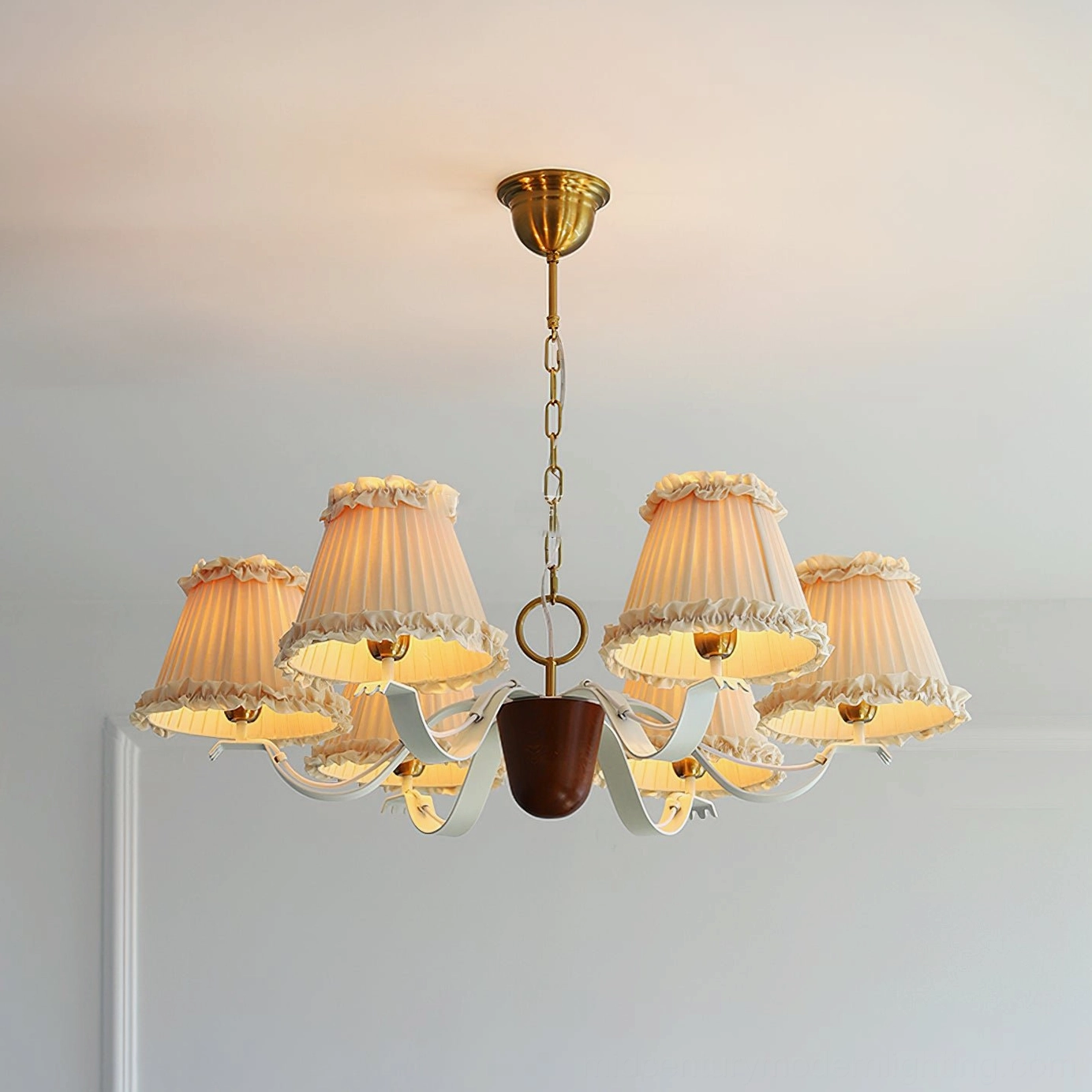 Beige pleated fabric chandelier with brass metal parts and dark wood accents, ceiling level view in minimalist home interior