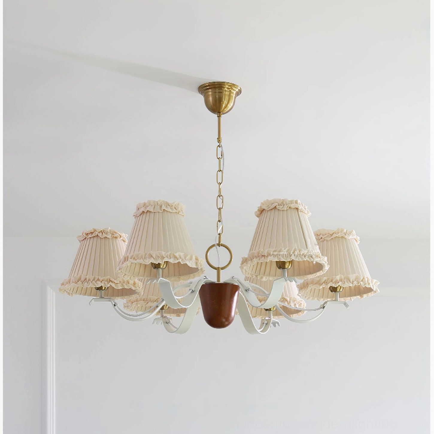Vintage-inspired fabric chandelier with beige pleated ruffled shades, brass chain, white curved arms, dark wood accent detail