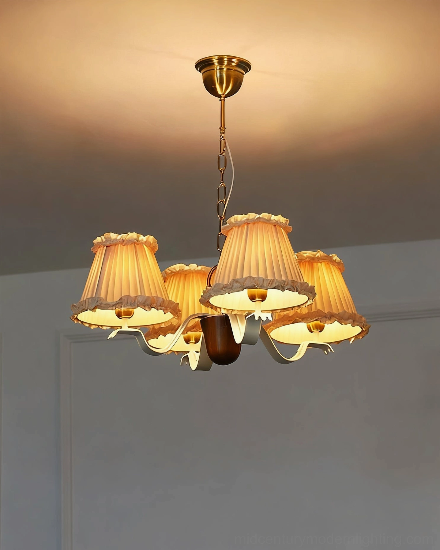 Illuminated fabric chandelier with warm glowing beige ruffled shades casting soft vintage light in home setting