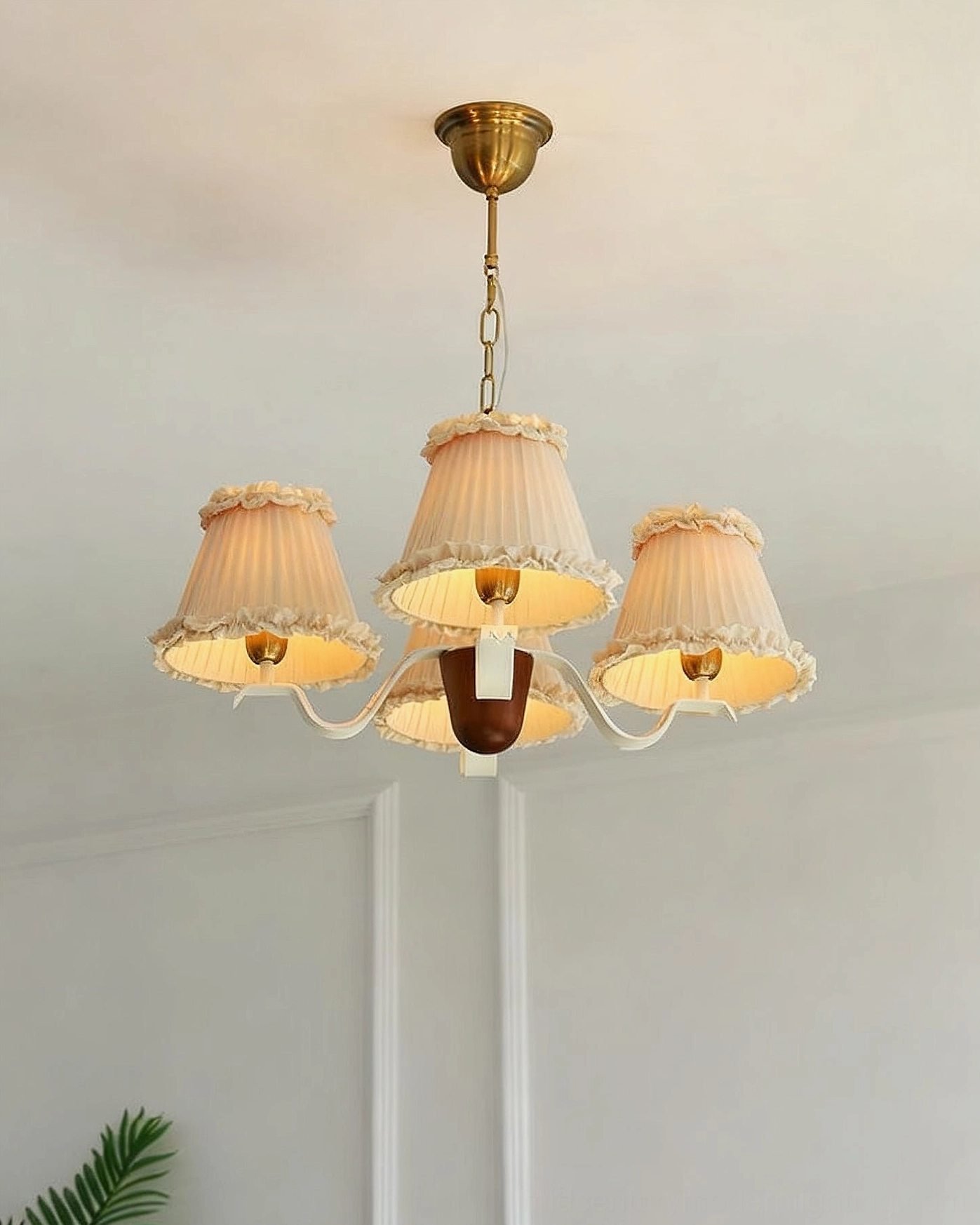 Fabric pendant light with beige pleated ruffled shades, vintage brass hardware, dark wood detail, three-quarter front view