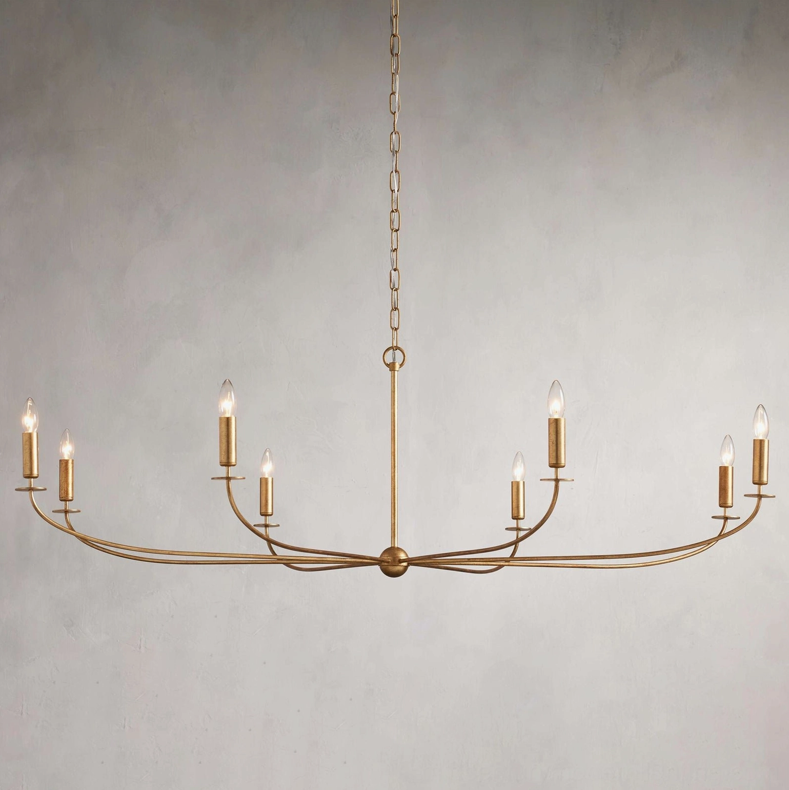 Emaani Candle Chandelier in Old Brass finish, sculptural arched arms with faux candleholders detail view